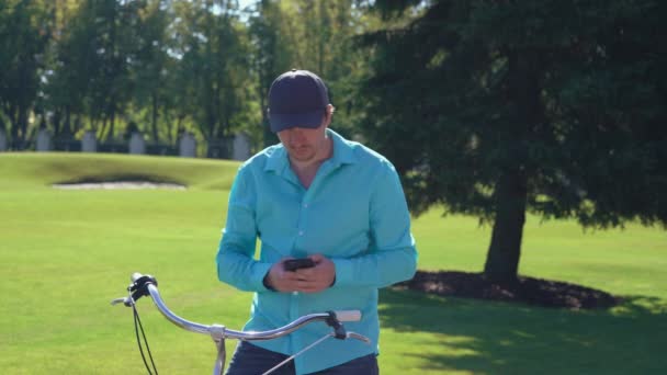 Pria yang menggunakan smartphone setelah mengendarai sepeda . — Stok Video