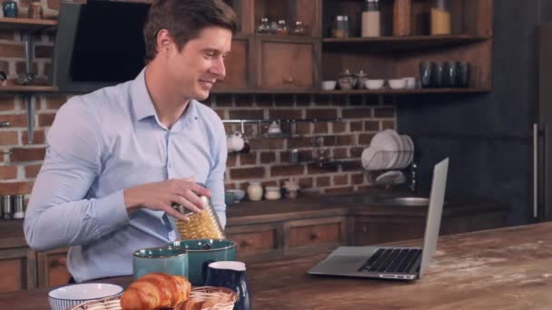 Male pours wheat flakes and speaking use internet. — Stock Video