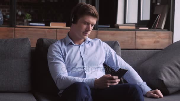 Чоловіки використовують навушники та мобільний телефон у квартирі . — стокове відео