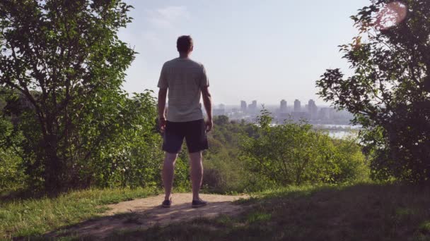 Guy mira el paisaje urbano desde la parte superior . — Vídeo de stock