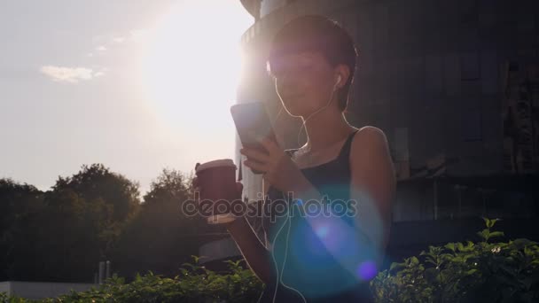 Dáma na chytrý telefon a poslouchat hudbu na ulici. — Stock video