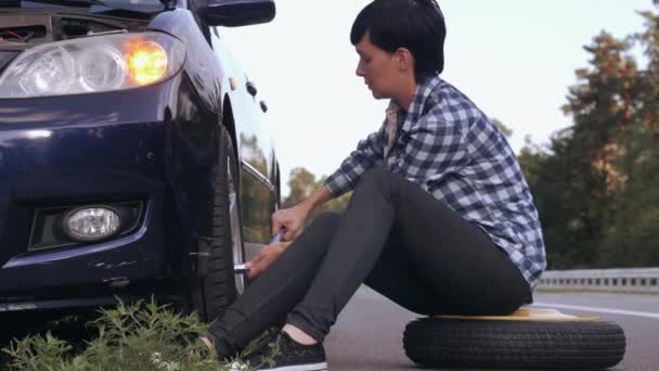Hembra cambiando un neumático al aire libre . — Vídeos de Stock