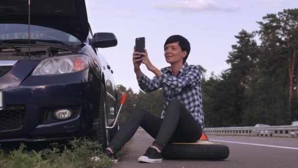 Caucasian female try to change a tire outdoors. — Stock Video