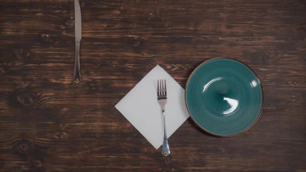 A zöld lemez mozog az asztalon, evőeszközök. — Stock videók