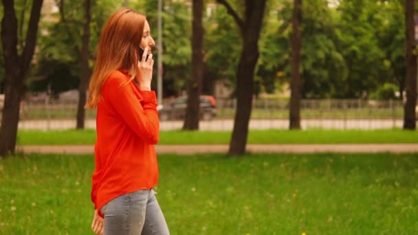 Redheaded businesswoman has a conversation by phone on the go — Stock Video