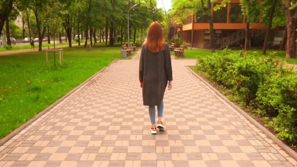 Businesswoman in grey coat strolls in spring city slow motion — Stock Video