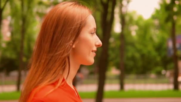 Boční pohled tvář mladá běloška žena v červené košili jít podél uličky — Stock video