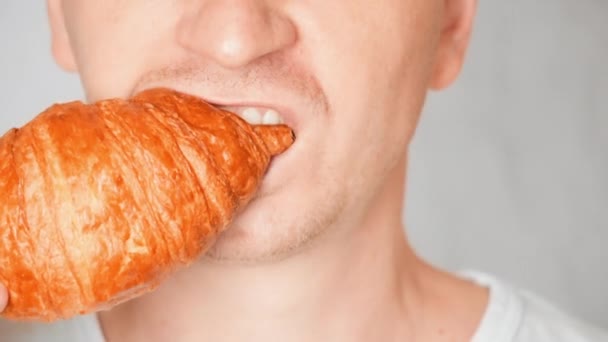 Close up gezicht eerlijk man eten croissant — Stockvideo