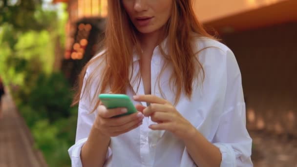 Cerrar hembra con auriculares que sostienen al aire libre móvil — Vídeo de stock