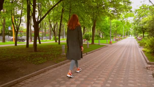 Giovane donna cammina nel parco della città — Video Stock