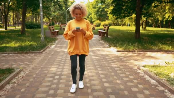 Hipster in gele trui met smartphone in de stad — Stockvideo