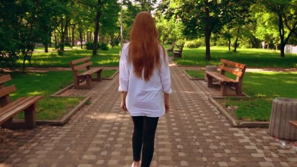 Невпізнавана жінка, що йде в парку — стокове відео
