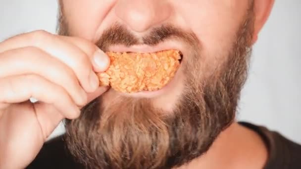 Взрослый бородатый мужчина ест жареных куриных ножек курицы — стоковое видео