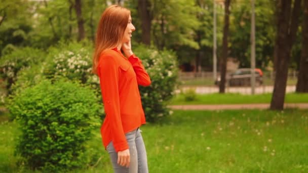 Vista lateral mulher gengibre andando na rua fala por smartphone — Vídeo de Stock