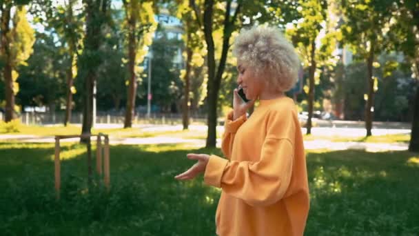 Sidan visa blond kvinna har telefon konversation utomhus — Stockvideo
