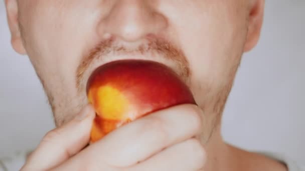 Close up face fair man eat nectarine — Stock Video