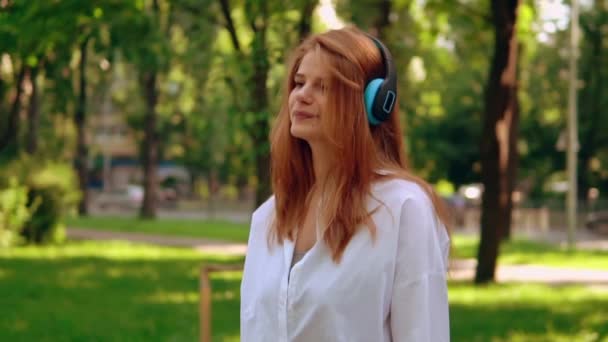 Mujer usando auriculares escuchando música al aire libre — Vídeos de Stock
