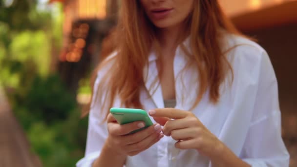 Női fehér ing és kék fejhallgató használata mobil — Stock videók