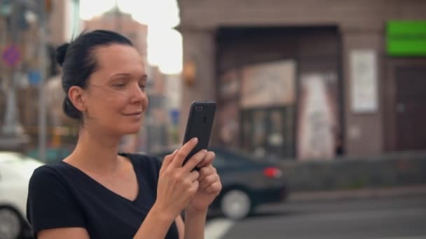 Brunette using mobile in summer town — Stock Video