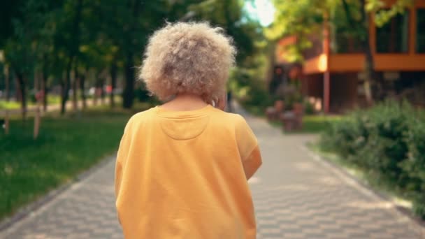 Back view blonde woman walks in park — 비디오