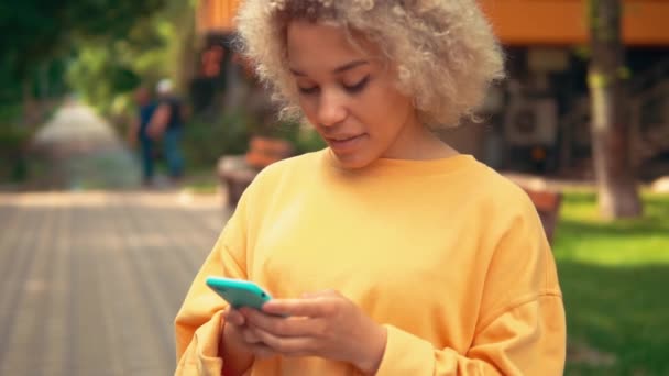 Blondine nutzt Smartphone im Freien — Stockvideo