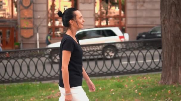 Вид збоку молода брюнетка гуляє в місті — стокове відео