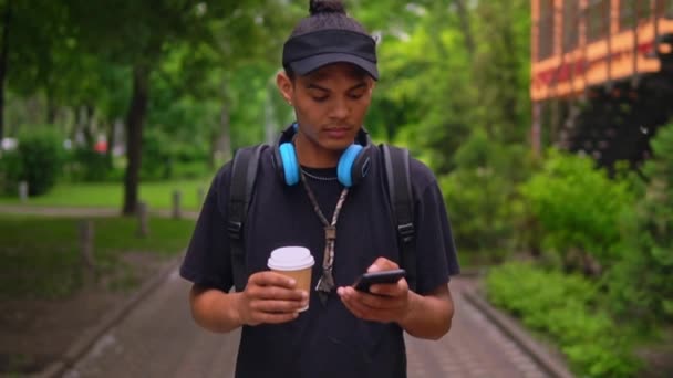 Pemuda menggunakan mobile berjalan-jalan di kota musim panas — Stok Video