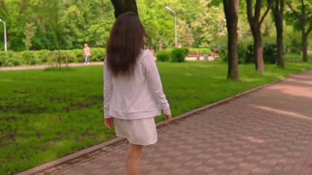 Назад вид женская ходьба в городском парке — стоковое видео