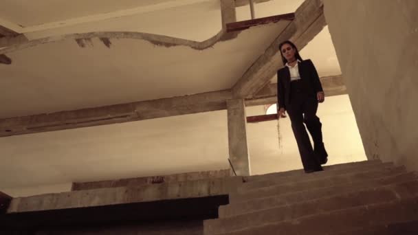 Женщина идет по лестнице в разрушенном здании — стоковое видео