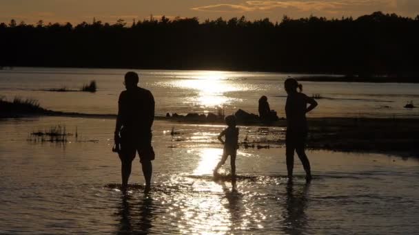 Семья наслаждается закатом на озере — стоковое видео