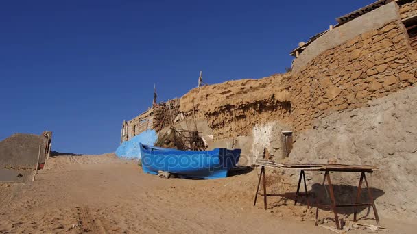 Casas de pescadores construidas en piedra caliza cerca del océano Marruecos Vista principal con el barco — Vídeo de stock