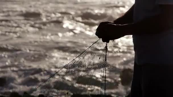 Um pescador em silhueta reparar uma rede de pesca Oceano em Marrocos câmera lenta — Vídeo de Stock