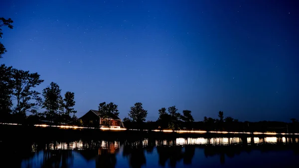 Kanada'da bir Gölü ile kırmızı bir ahır ve arabalar geçen ışıklar gece çekimi