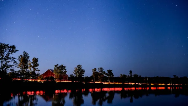 Kanada'da bir Gölü ile kırmızı bir ahır ve arabalar geçen ışıklar gece çekimi