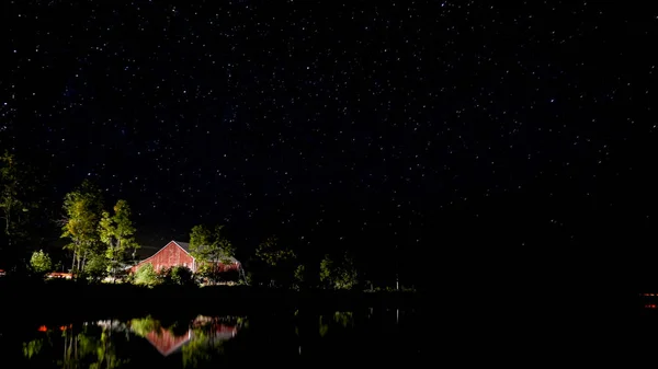 Kanada'da bir Gölü ile kırmızı bir ahır ve arabalar geçen ışıklar gece çekimi