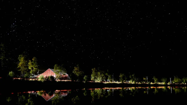 Kanada'da bir Gölü ile kırmızı bir ahır ve arabalar geçen ışıklar gece çekimi