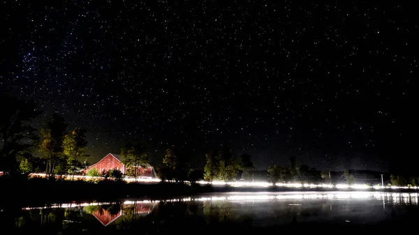 Kanada'da bir Gölü ile kırmızı bir ahır ve arabalar geçen ışıklar gece çekimi