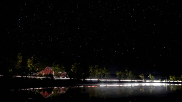 Kanada'da bir Gölü ile kırmızı bir ahır ve arabalar geçen ışıklar gece çekimi