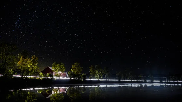 Kanada'da bir Gölü ile kırmızı bir ahır ve arabalar geçen ışıklar gece çekimi