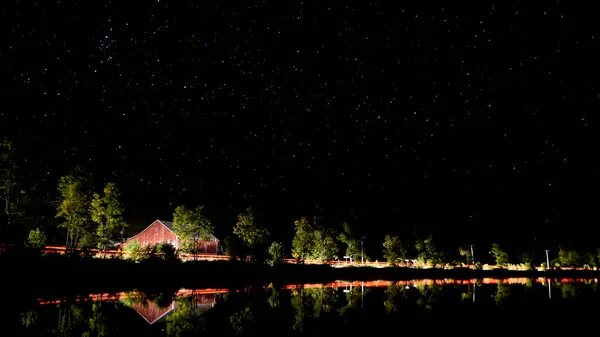 Kanada'da bir Gölü ile kırmızı bir ahır ve arabalar geçen ışıklar gece çekimi