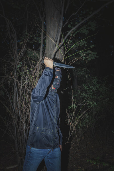 man with mask and knife in the wood