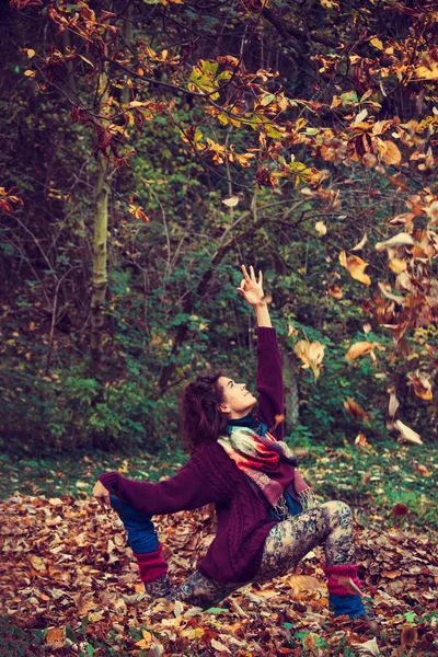 Giovane donna pratica yoga in foglie di autunno — Foto Stock