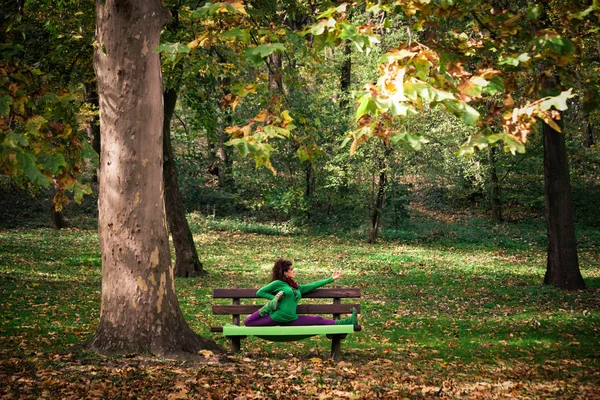 Młoda kobieta praktyki jogi na ławce w parku — Zdjęcie stockowe