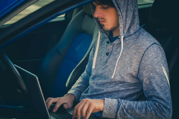 Hacker sentarse en el coche con su computadora portátil — Foto de Stock