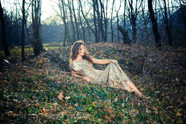 Elegant young woman sit on ground in forest — Stock Photo, Image