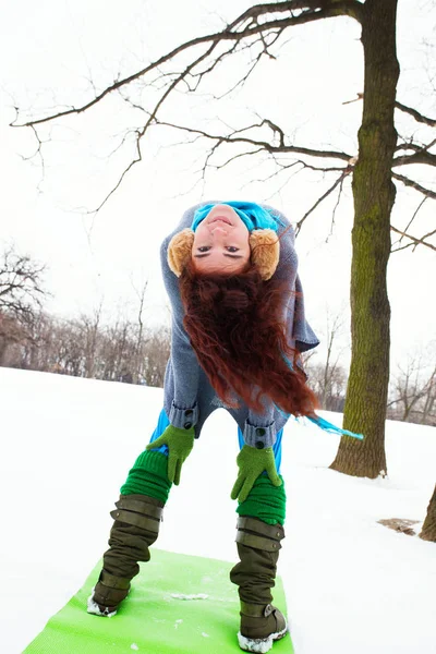 Молода жінка робить йогу на снігу в парку — стокове фото