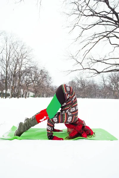 Νεαρή γυναίκα να κάνει γιόγκα στο χιόνι στο πάρκο — Φωτογραφία Αρχείου