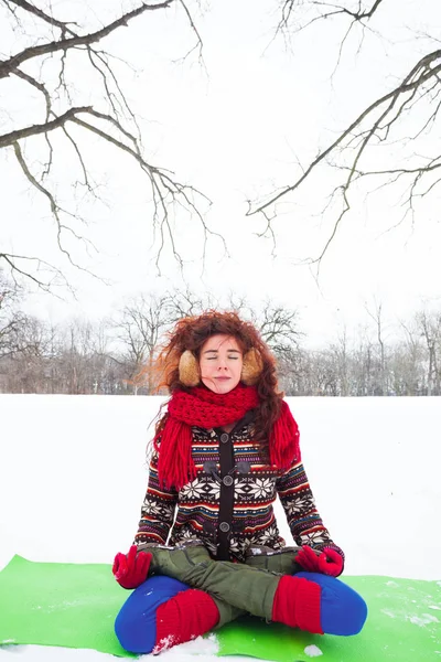 Молода жінка робить йогу на снігу в парку — стокове фото