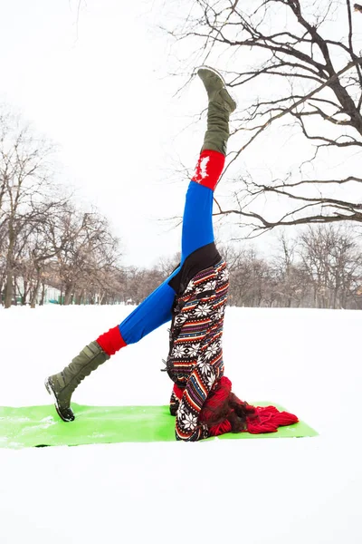 Молода жінка робить йогу в снігу в парку — стокове фото