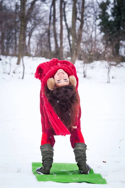 Усміхнена молода жінка робить йогу на снігу в парку — стокове фото